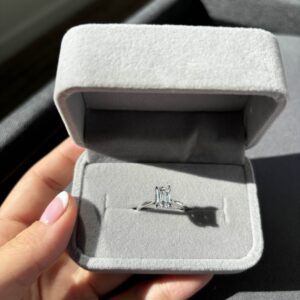 image of a client holding their 1.5 ctw emerald cut engagement ring